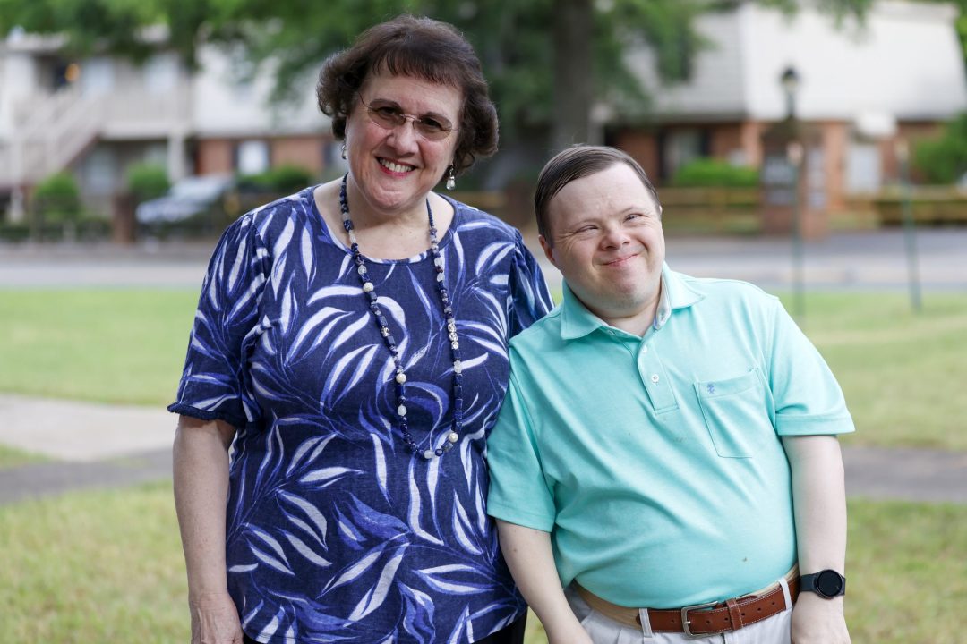 Smiling woman and man with Down syndrome standing together outdoors
